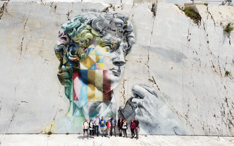 hikers in front of kobra mural in carrara marble quarries