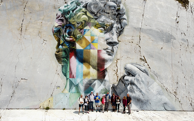 camminatori davanti al murale di kobra, cave di marmo di carrara