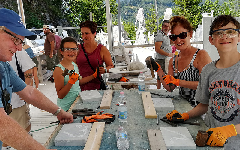 family with kids having fun carving marble