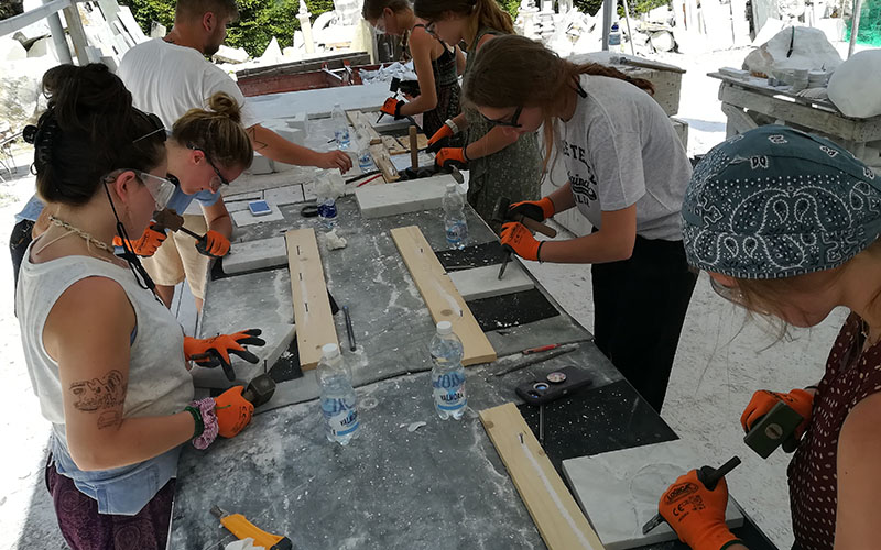 ragazze al lavoro per scolpire il mare a carrara