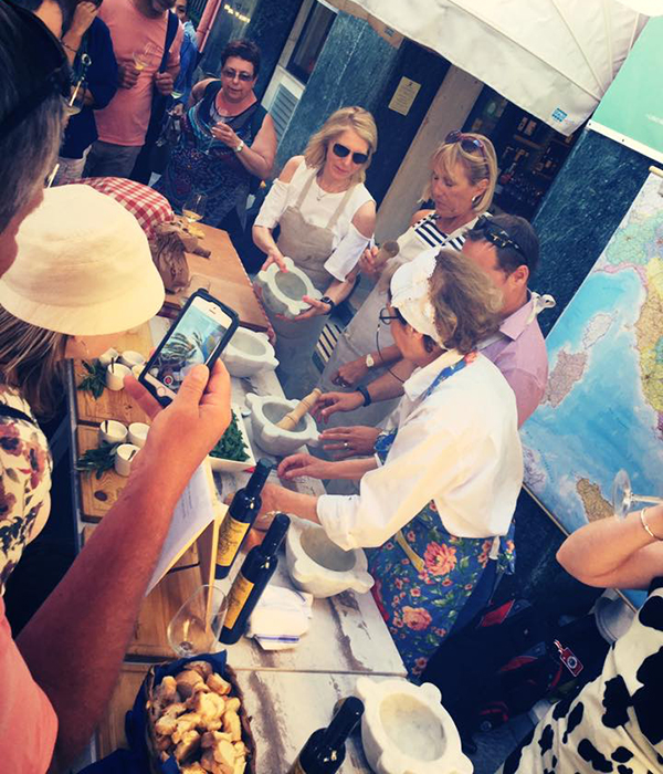 people punding ingredients for the making of pesto sauce