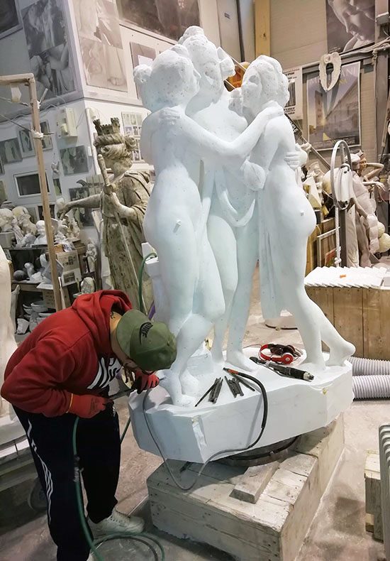 carrara, laboratorio scutura scultore al lavoro su copia delle tre grazie di canova